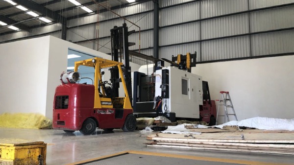 Instalación y movimiento de maquinaria industrial con montacargas.